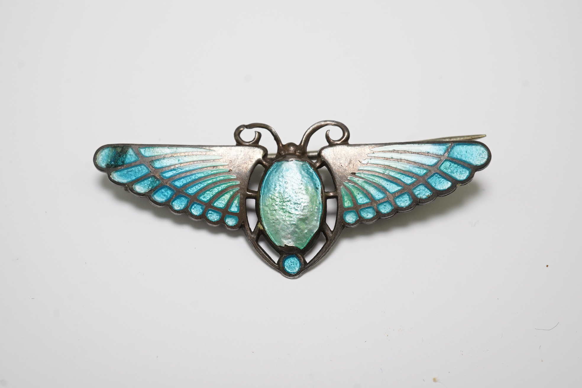 An Egyptian Revival silver and enamelled oval pendant, 88mm and a silver enamelled stylised butterfly brooch.